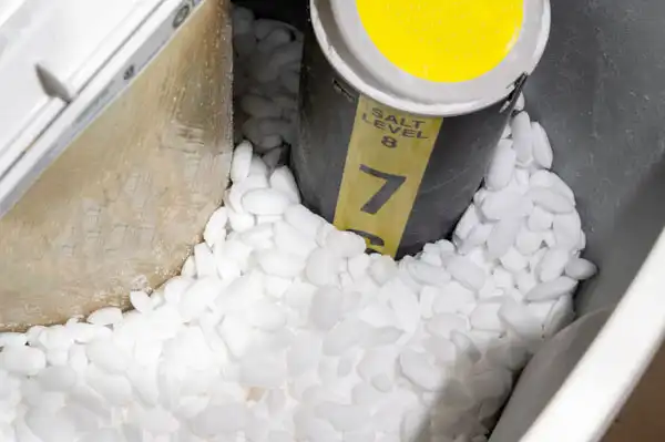 Water softener tank filled with white salt pellets, with a yellow-capped salt level indicator marked at level 7.